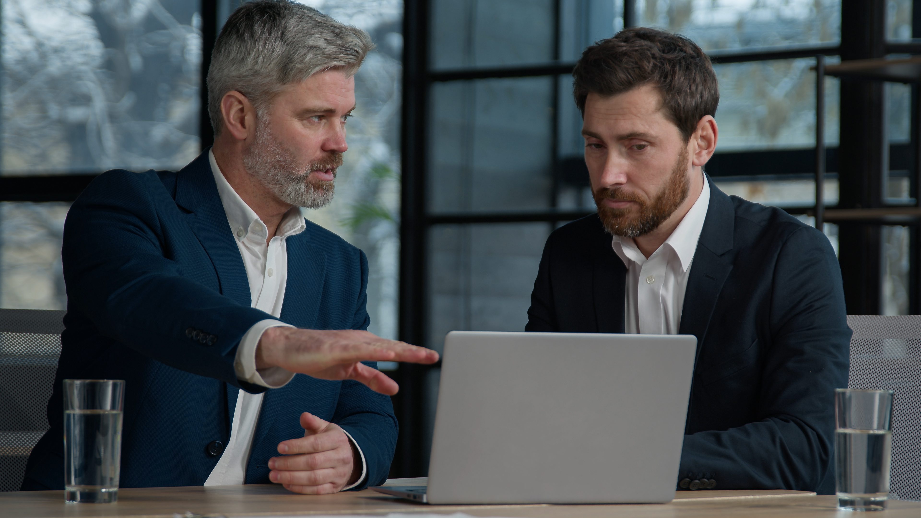 Two businessmen discussing work at a laptop.